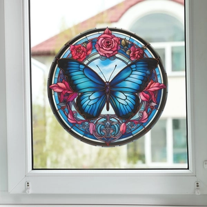 Detail der runden Fensterfolie in Buntglasoptik mit blauem Schmetterling und Blumenmuster