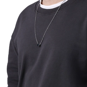 Minimalist silver titanium steel chain with a small black square cube pendant on grey sweater