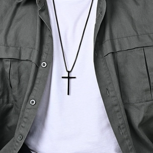Collana con croce nera minimalista da uomo, mostrata su un modello con abbigliamento a strati