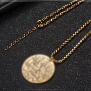 Makrodetail einer goldenen Edelstahl-Boxkette mit Karabinerverschluss auf dunklem Grund