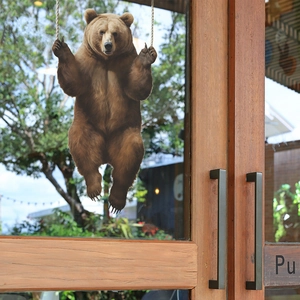 Detail of cute 3D brown bear glass window sticker on a minimalist wooden door