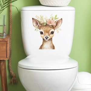 Cartoon fawn wall sticker with floral crown on white toilet in a cozy bathroom setting