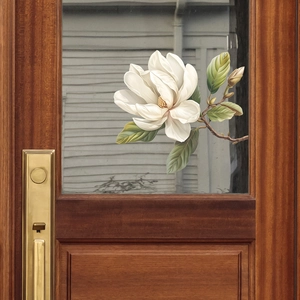 Detail of translucent magnolia flower glass sticker on wooden door with brass lock