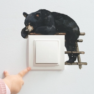 Detail of creative black bear wall sticker surrounding a white light switch in a nursery