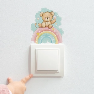 Detail of hand-painted rainbow bear wall sticker on a white light switch in a child room