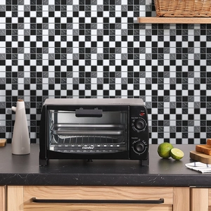 Detail of black and white checkerboard wall tiles behind a compact black electric oven