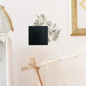Close-up of black double light switch decorated with white magnolia floral wall stickers