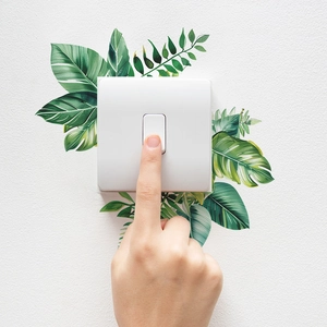 Detailed view of tropical plant leaf wall stickers applied around a white light switch