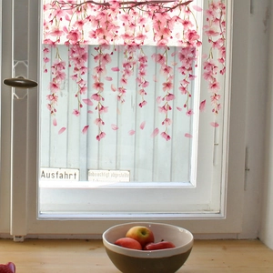 Pink cherry blossom window clings showing floral branches on glass in a sunlit room
