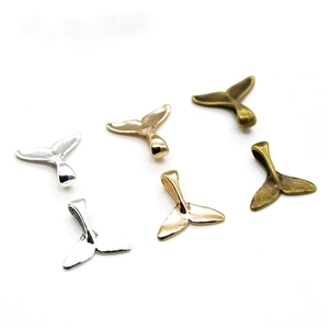 Detailed view of whale tail charms in various metal finishes for jewelry making