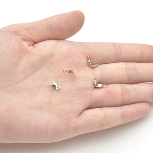 Silver clamshell bead tips for DIY jewelry making shown on a palm for scale