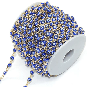 Detail of blue evil eye beads with golden copper chain on a white plastic spool