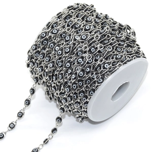 Close-up of black and white evil eye bead chain on white spool for DIY jewelry making