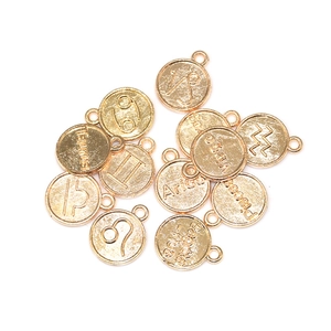 Macro view of gold alloy zodiac charm pendants with engraved symbols for DIY jewelry