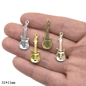 DIY retro guitar charms in four metal finishes held in palm for scale, size 31x11mm