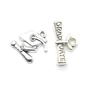 Macro detail of antique silver graduation charms featuring a mortarboard and graduate scroll