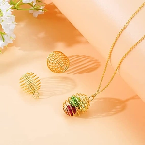 Collana con ciondolo a gabbia a spirale dorata con perline di strass su sfondo arancione