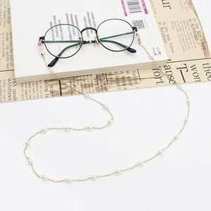 Retro round black glasses with gold chain and white imitation pearls on newspaper background