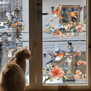 Detail of floral and bird window stickers on a wood frame with a cat watching