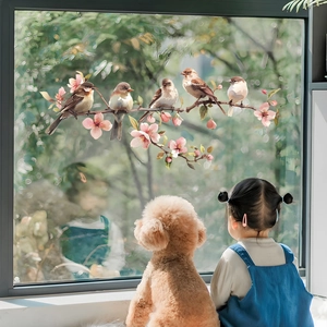 Detail view of decorative window cling featuring birds and pink blossoms in home setting