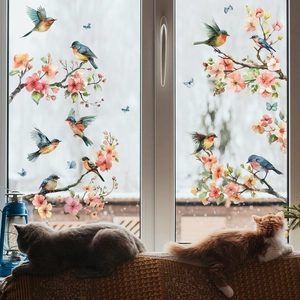 Detailed close-up of decorative floral and bird window clings on a glass pane in home setting