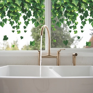 Close-up of green ivy leaf window decals in a modern kitchen setting with running water