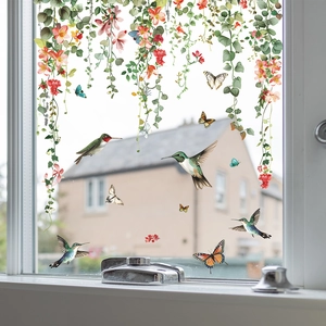 Detail of colorful hummingbird and floral vine window clings on a transparent glass