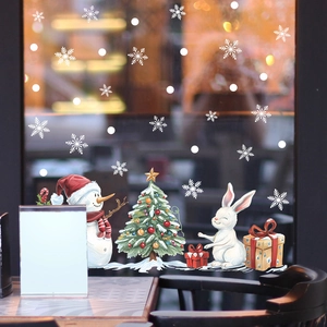 Close-up of white Christmas window decals featuring snowman, rabbit, and snowflakes