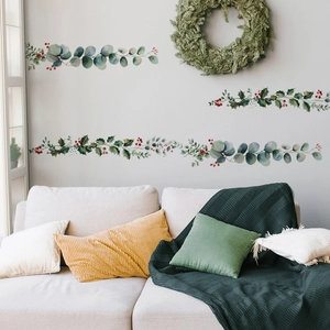 Detail showing green plant wall stickers with eucalyptus leaves above a cozy living room sofa