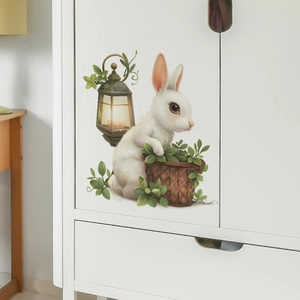 Detail of cartoon white rabbit wall sticker with leafy basket and retro lantern on white cabinet