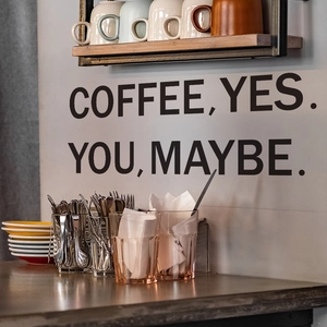 Detail of matte black coffee wall decal with slogan 'COFFEE, YES. YOU, MAYBE.' for kitchen decor
