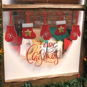 Red Christmas mitten and stocking decorations with snowflake embroidery hanging on a wooden window