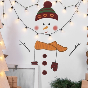 Detailed view of snowman wall decal set with carrot nose and branch arms on a white wall