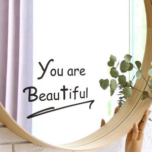 Minimalist round wooden mirror with You are Beautiful wall sticker on white brick background