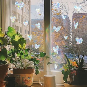 Detailed close-up of iridescent heart window clings creating rainbow light on a windowsill