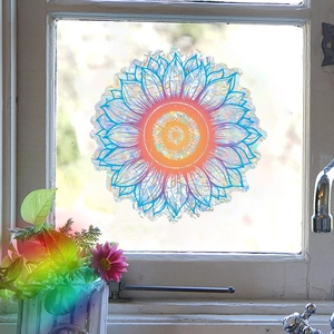Rainbow effect prism window sticker with mandala floral design casting sunlight on plants