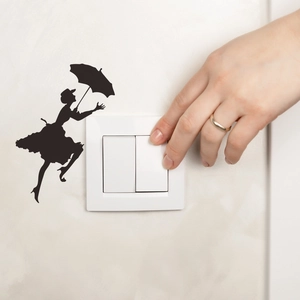Black silhouette wall sticker showing a woman with umbrella near a light switch decor