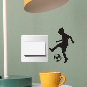 Detail of black silhouette wall sticker showing a boy playing soccer by a light green switch