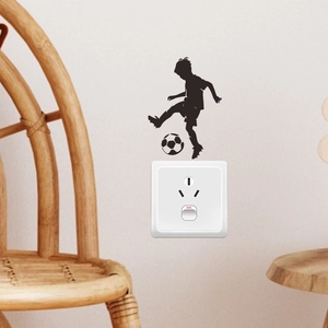 Black silhouette wall sticker of a boy kicking a soccer ball above a light switch