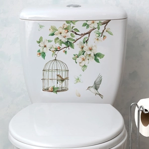 Floral branches and birdcage decals applied on a white ceramic toilet tank surface