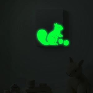 Adesivo murale scoiattolo luminoso con effetto bagliore verde su decorazione interruttore