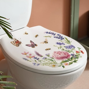 Close-up of watercolor floral stickers with butterflies and bees on a white toilet lid
