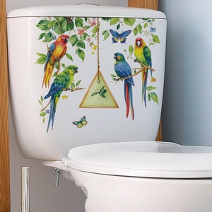 Parrot and green leaf decorative stickers applied to a white ceramic toilet tank surface