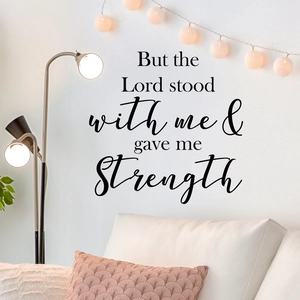 Matte black vinyl wall decal with religious quote on a white wall above a sofa