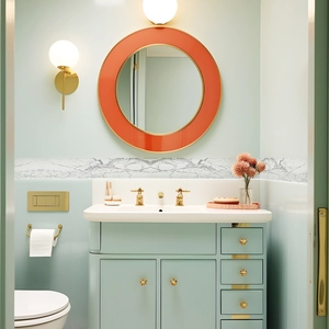 Modern bathroom decor with orange circular wall mirror and white marble texture wall sticker
