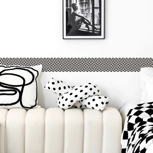 Modern white knotted pillow with black polka dots on white sofa with geometric wall stickers