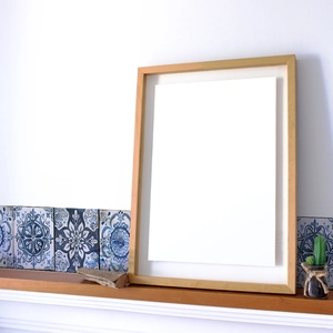 Detail shot of a minimalist wooden picture frame against a vintage patterned tile background