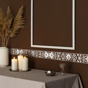 Close-up of silver embossed floral wall border sticker on dark brown wall in retro decor