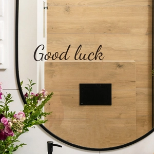 Black vinyl Good Luck sticker decal on a round wall mirror for home bathroom decor