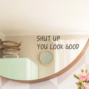 Modern black vinyl wall decal with Shut Up You Look Good slogan on a round wooden mirror